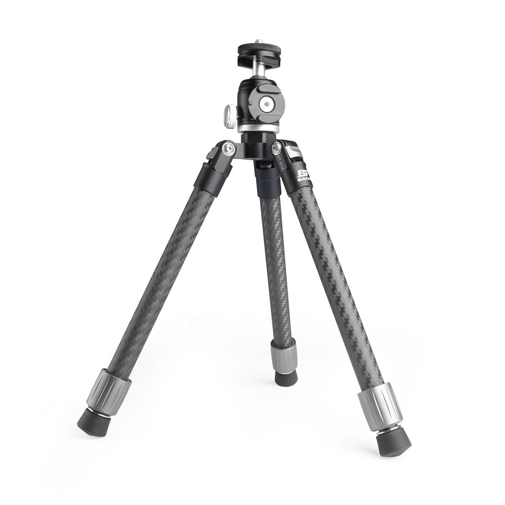 A carbon fiber tripod with a black and silver metal head and leg caps, photographed on a seamless white background.